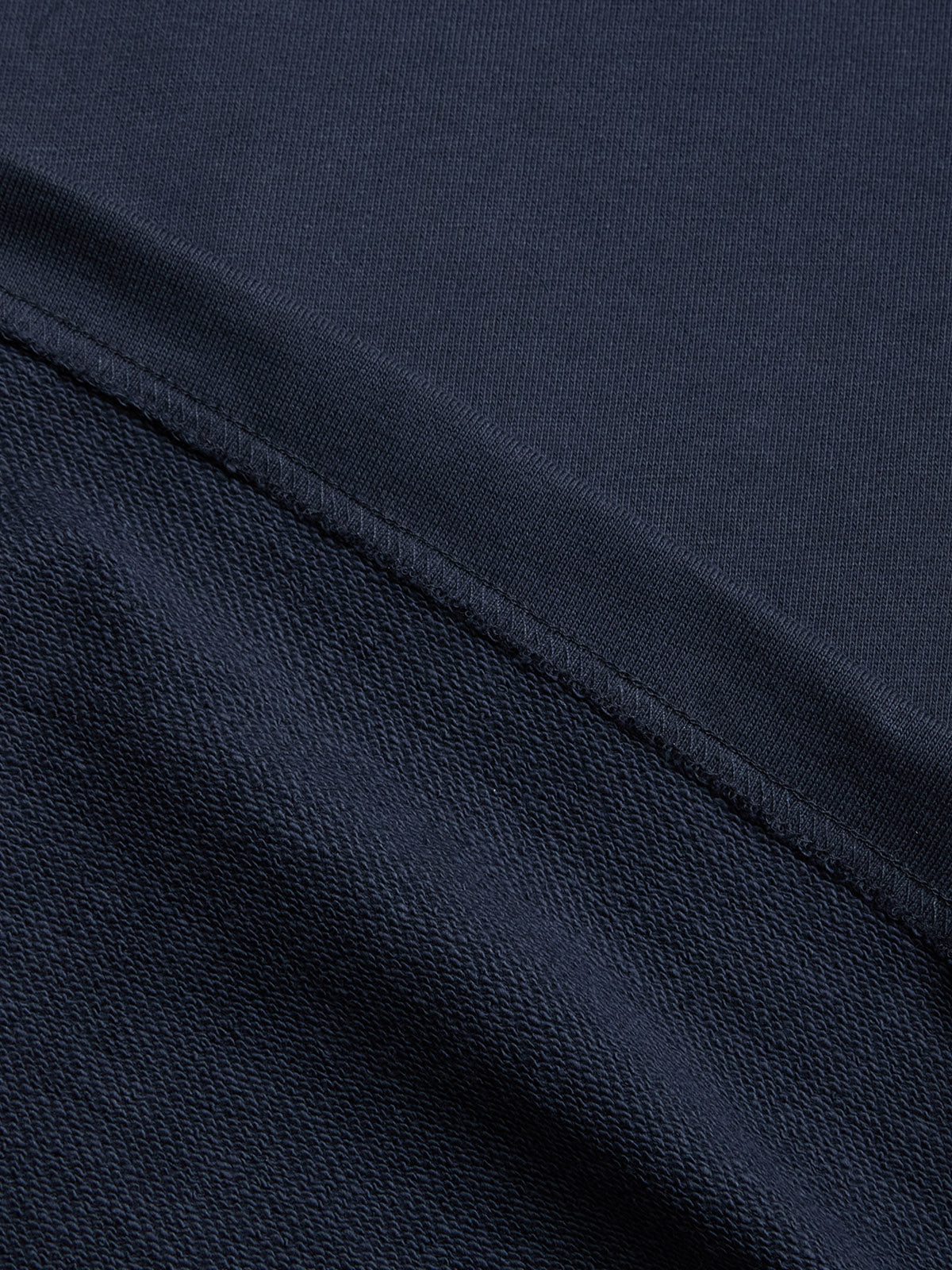 Close-up of the BGclubhouse Rugby Sweatshirt – Navy by Blue de Gênes, highlighting its dark blue cotton jersey with a visible seam and the Clubhouse Champs Collection's signature smooth and textured surfaces.