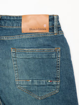 Close-up of the back pocket and waistband of Vinci Topaz Vintage Jeans - Used by Blue de Gênes, in blue comfort stretch denim, featuring a brown leather patch with the brands name and logo.