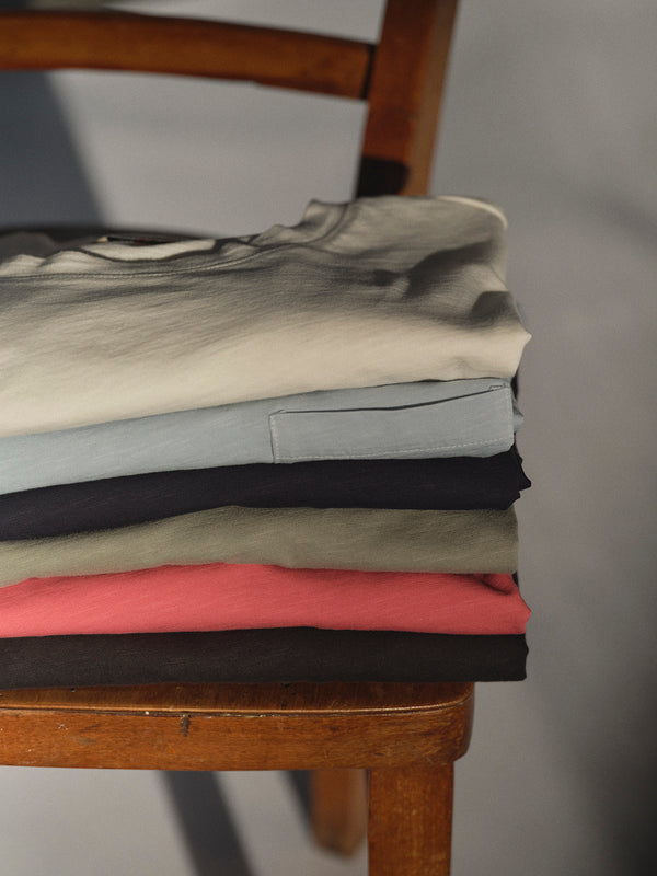 A neatly folded BGoscar T-Shirt - Coral by Blue de Gênes, made from 100% cotton, rests on a wooden chair.