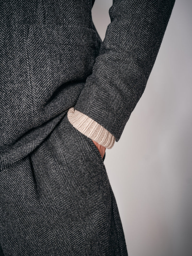 A person stands with a hand in their pocket wearing Blue de Gênes Kyoto Pant - Black Pattern paired with a beige sweater, in front of a plain light background.