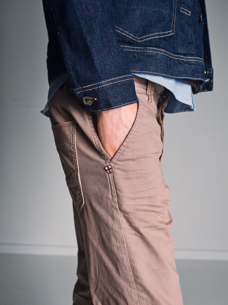 A person stands with one hand in their pocket, wearing Blue de Gênes Paulo Pavia 1 V2 Chino – Fungi, crafted from cotton stretch fabric. The photo is cropped from the chest down, highlighting this stylish and casual look.