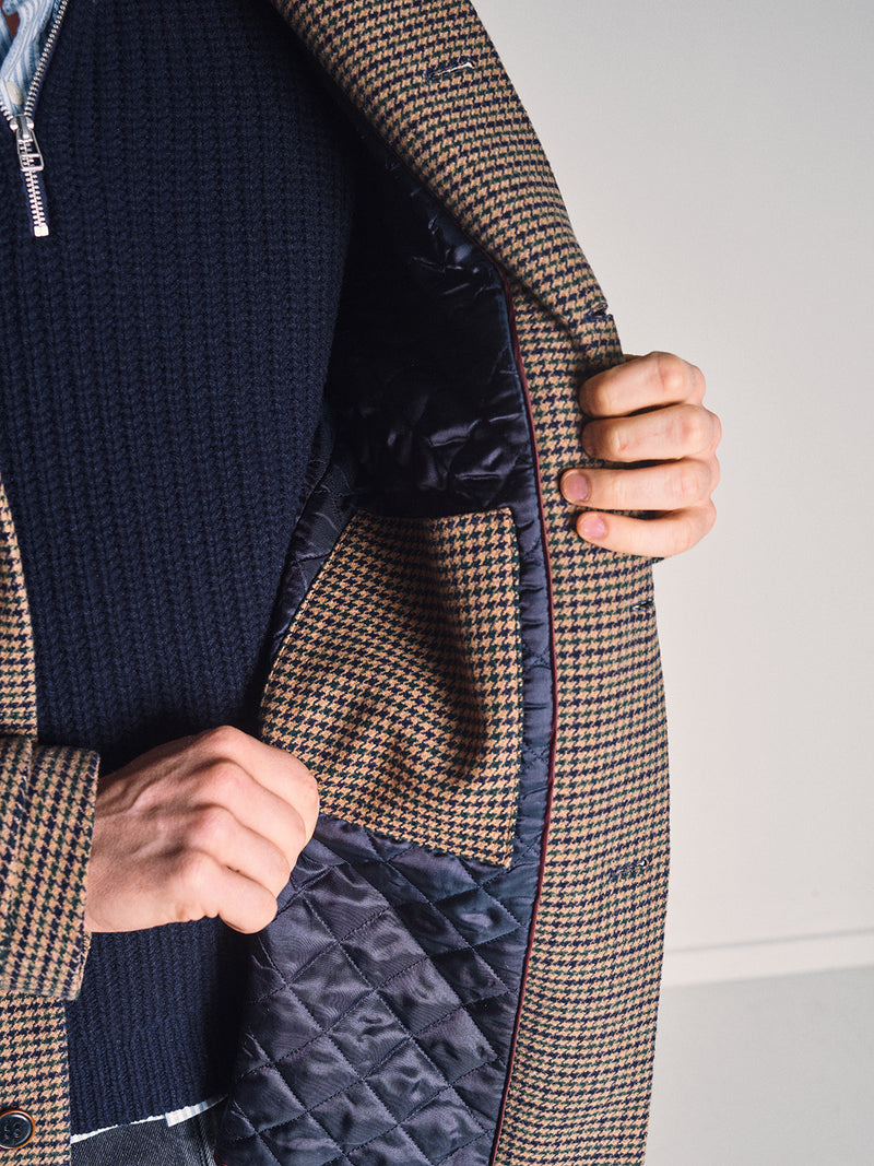 A person opens the Blue de Gênes Massone Check Coat - Multi Check to reveal its quilted lining and inner pocket in matching check fabric—perfect for a refined winter look.