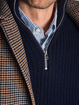 Close-up of a person wearing the Blue de Gênes Yomaha Halfzip Knit in navy over a blue and white striped collared shirt, layered with a brown and navy houndstooth coat. The person's neck and lower face are partially visible.