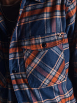 Close-up of the Blue de Gênes Yodo Check Overshirt - Multi Check in a relaxed fit, featuring blue, orange, and white plaid, a buttoned chest pocket, visible collar and buttons. The soft-touch fabric looks warm and comfortable.