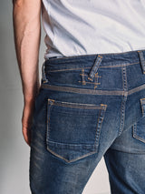 Close-up of a person wearing Blue de Gênes Repi Dark Vintage Jeans - Mid Blue Denim, with focus on the back pockets and waistband. The jeans are slightly oversized and sit low on the hips for a relaxed, casual look.