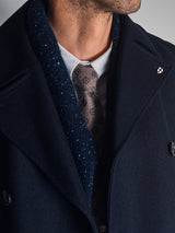 Close-up of a man wearing a navy overcoat, textured blazer, white shirt, and the Nekutaki Tie #E - Sand Pattern by Blue de Gênes. Only his lower face and upper torso are visible.