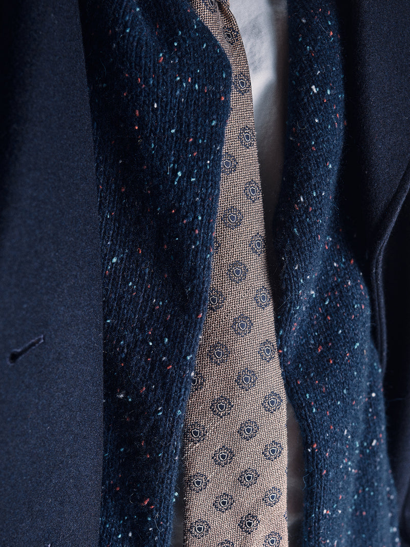 Close-up of a person wearing Blue de Gêness navy jacket and scarf, paired with the Nekutaki Tie #E – Sand Pattern, layered over a crisp white shirt—highlighting timeless tailoring.