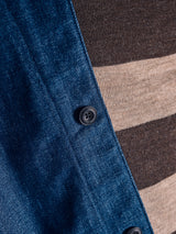 Close-up of the Blue de Gênes Yuma Fano Jacket in denim blue, a heavy cotton blend with black buttons, styled over a brown and beige striped knit top.