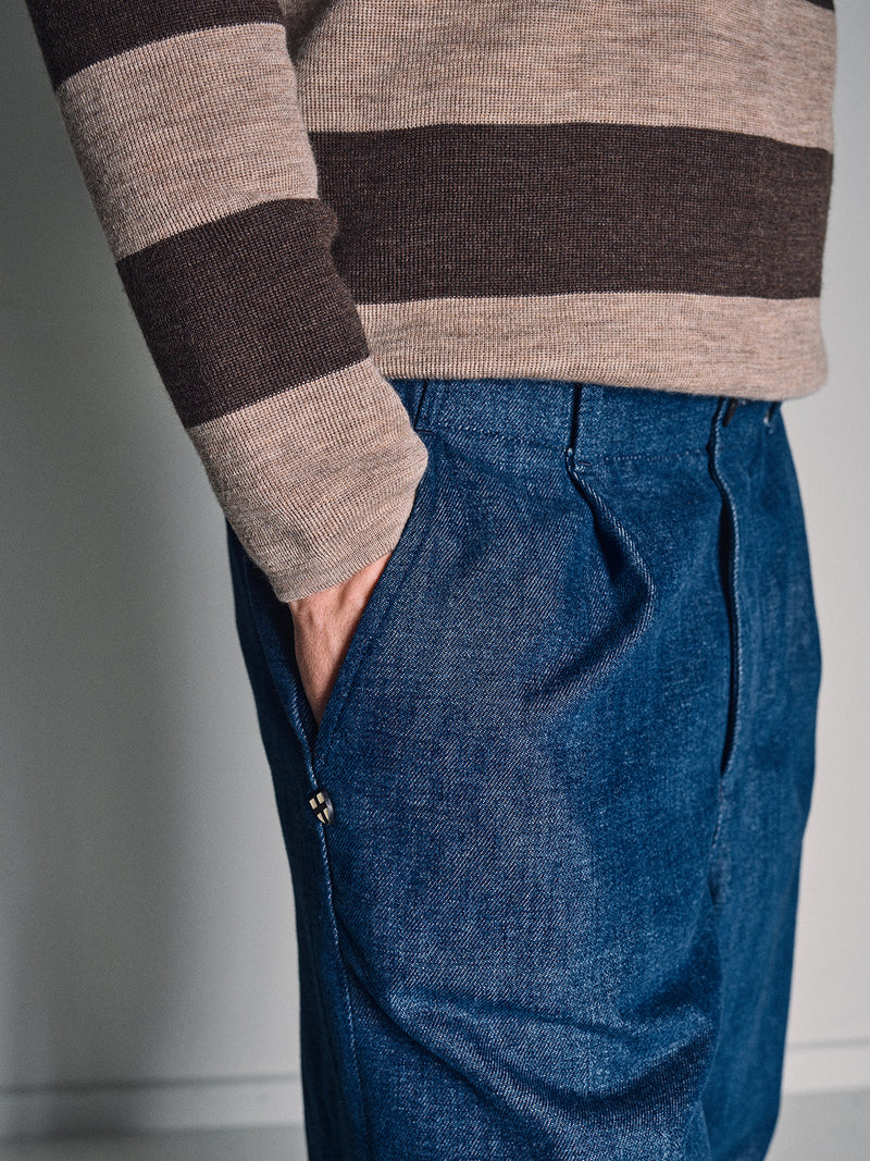 A person stands with one hand in their pocket, showing only the torso and upper legs, wearing the Blue de Gênes Toyama Stripe Knit L/S - Oat sweater and blue jeans.