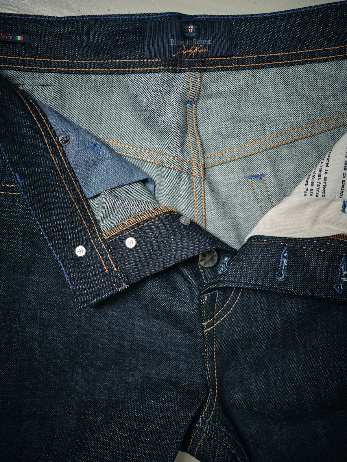 Close-up of Blue de Gênes Giacomo Selvedge V2 Jeans in raw, dark blue denim, with the fly open to reveal inside fabric, stitching, button, and pocket lining.