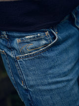 Close-up of the front pocket area of Blue de Gênes Marco Used Jeans – Used, made from 100% cotton denim with visible stitching and a small coin pocket. A dark top appears partially above the waistband.