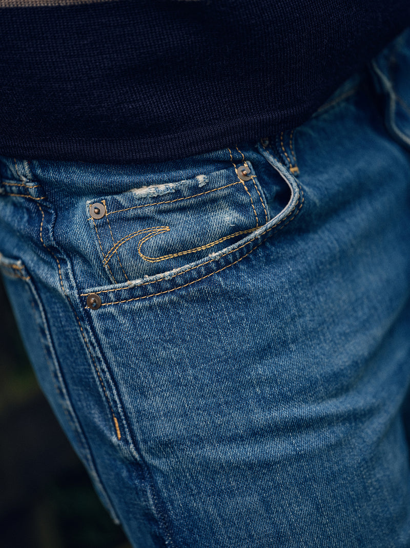 Close-up of the front pocket area of Blue de Gênes Marco Used Jeans – Used, made from 100% cotton denim with visible stitching and a small coin pocket. A dark top appears partially above the waistband.