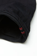 Close-up of the hem on Blue de Gênes Repi 3325 Black Jeans, highlighting durable black denim with detailed stitching and two small lines of red thread. The fabric features a structured, slightly textured finish.