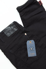 A pair of Blue de Gênes Repi 3325 Black Jeans in slim-fit black denim, neatly folded to reveal a leather brand patch above the back pocket and a dark blue tag, with visible durable stitching and fabric.